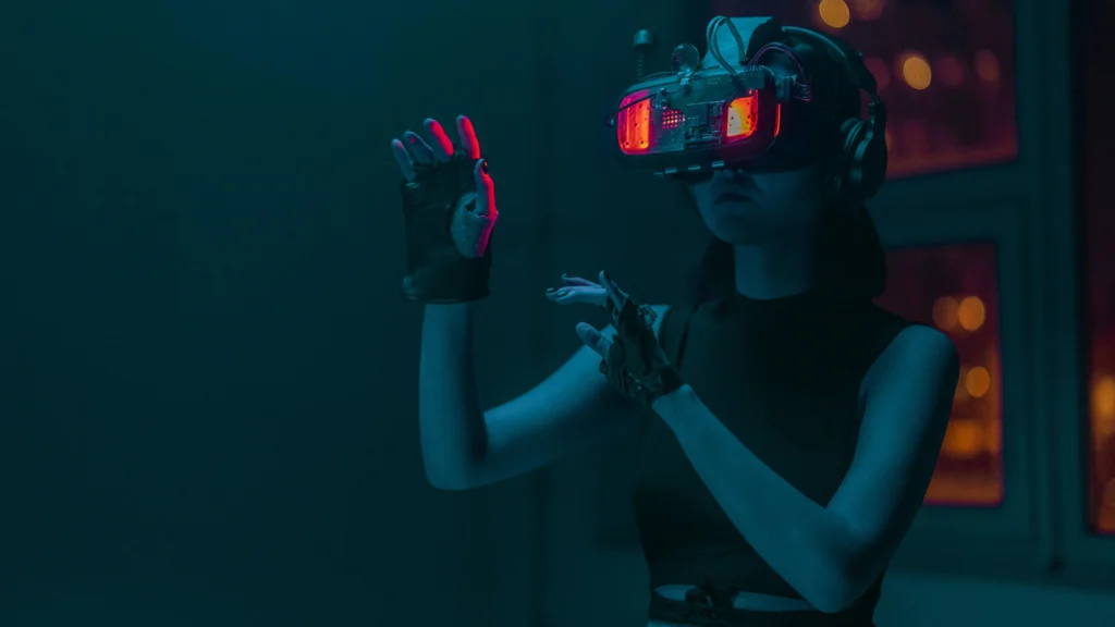 A female hacker wearing a black top using Virtual Reality features with her donned VR goggles headset by gesturing with both hands in mid-air.